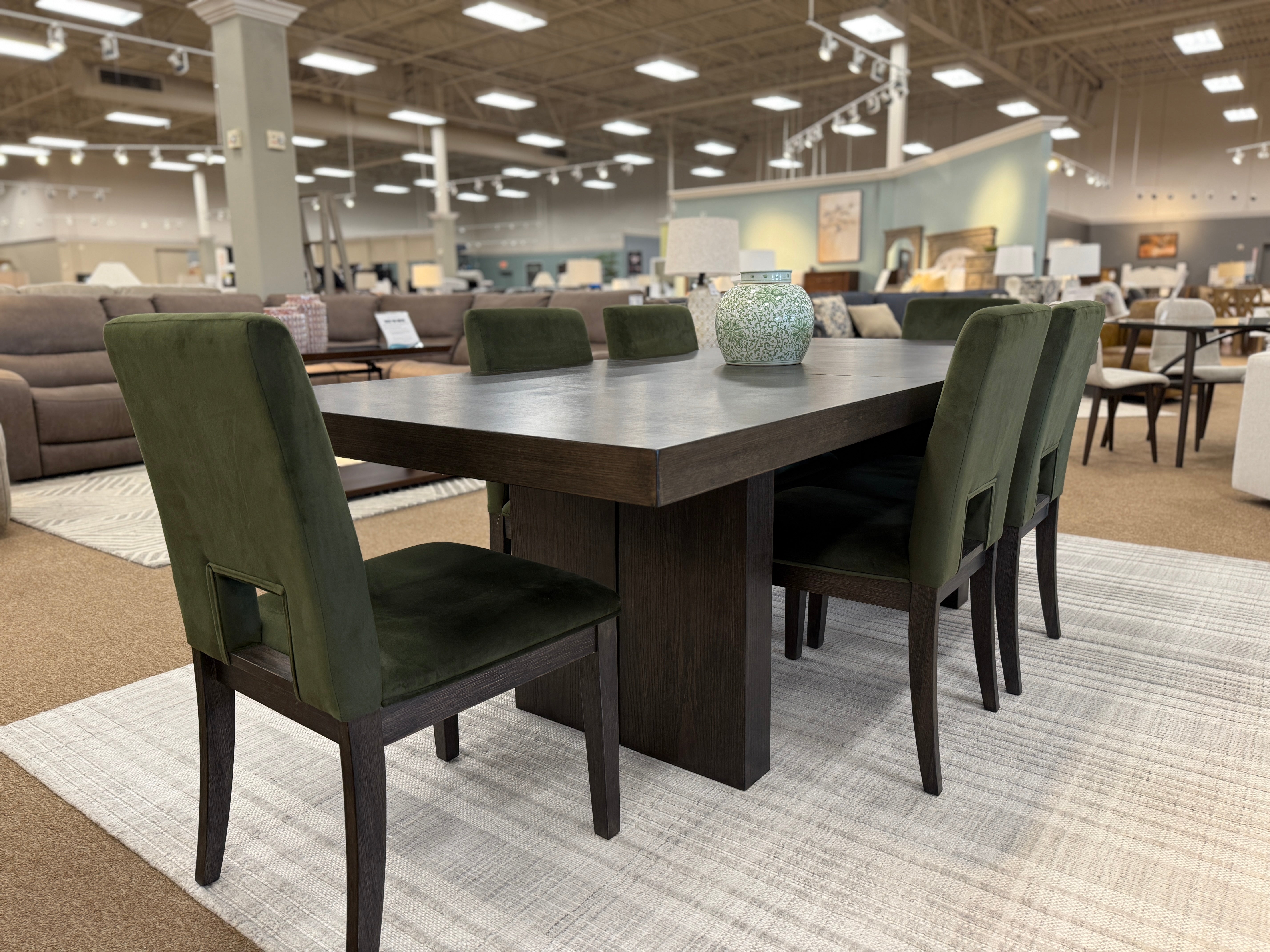 Dining table with green velvet chairs in furniture store showroom