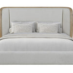 A modern King platform bed with a tall, upholstered headboard and footboard in a light gray fabric, framed by natural wood trim, styled with two textured gray pillows and a matching gray throw blanket.