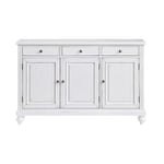 A white wooden sideboard cabinet with three drawers on top and three paneled doors below, featuring small round silver knobs and turned feet, shown against a plain white background.