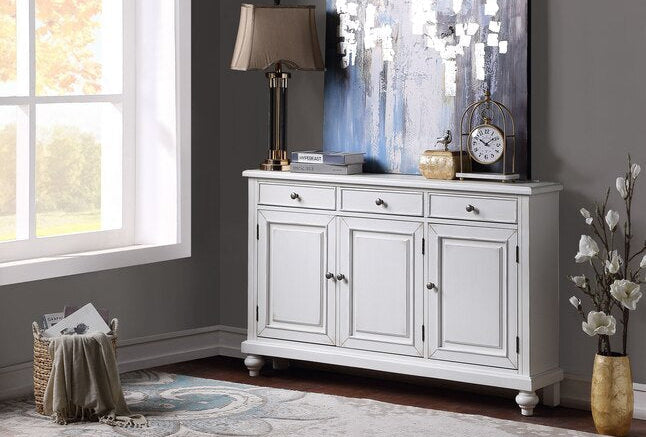 White sideboard in a room with decor elements like a lamp, clock, and decorative items.