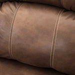 Close-up of a brown leather or faux-leather upholstered cushion with visible cream-colored contrast stitching.