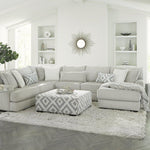 Modern living room with a gray sectional sofa, patterned ottoman, and decorative elements.