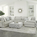 Modern living room with a gray sectional sofa, patterned ottoman, and decorative elements.