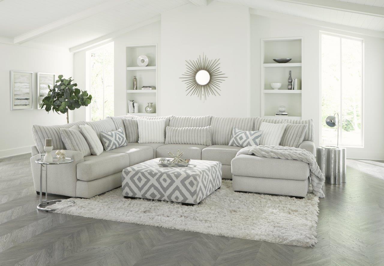 Modern living room with a gray sectional sofa, patterned ottoman, and decorative elements.