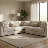 A light beige sectional sofa with matching throw pillows in a modern, sunlit living room with wood floors and a large area rug.