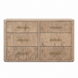 A six-drawer wooden dresser with a light oak finish and brass handles, shown against a plain white background.