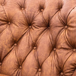 A close-up of a brown tufted leather armchair in a furniture showroom.