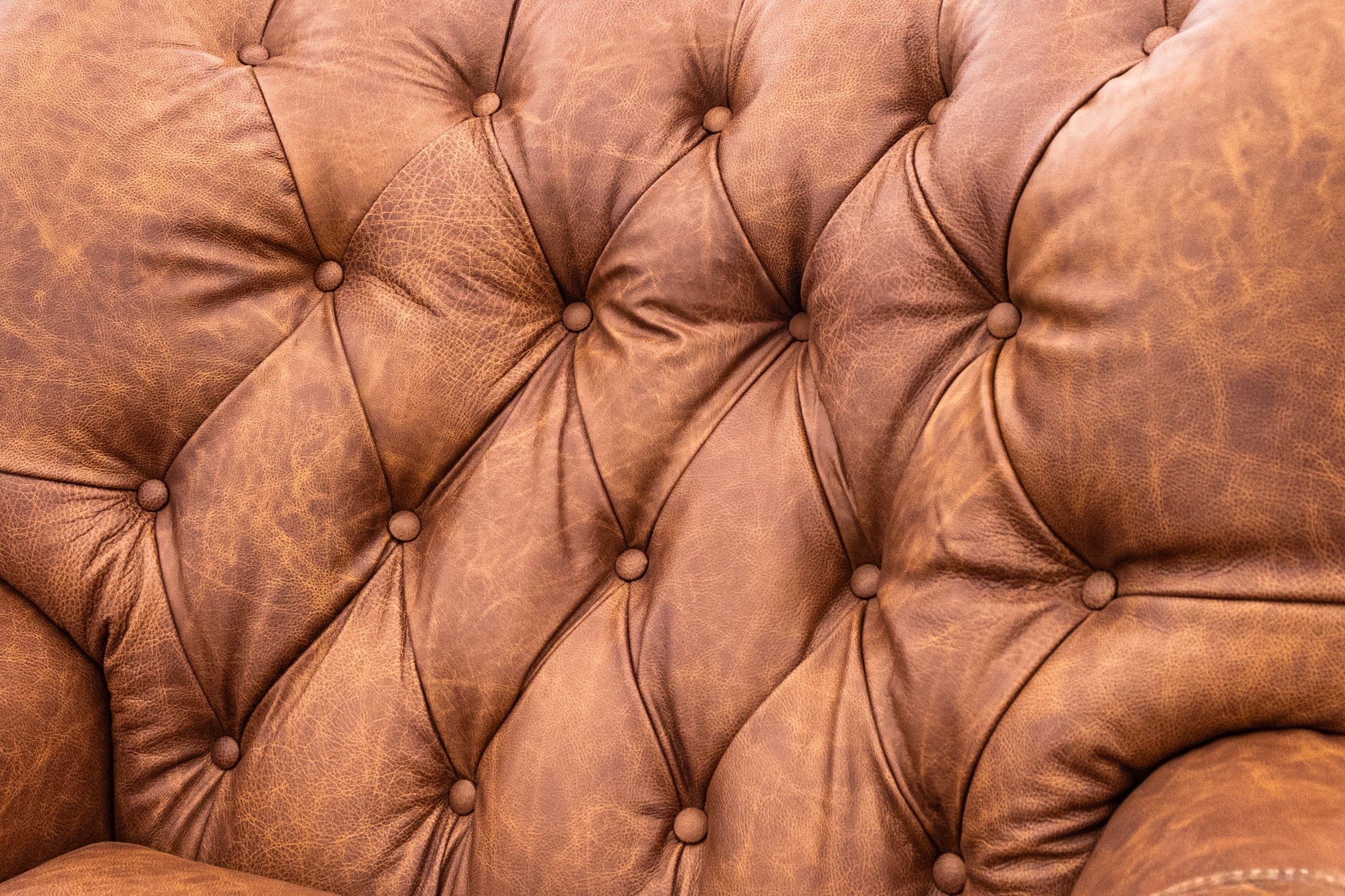 A close-up of a brown tufted leather armchair in a furniture showroom.