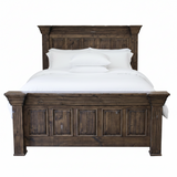 A dark brown wooden bed frame with a tall paneled headboard and matching footboard, styled with white bedding and pillows against a plain white background.