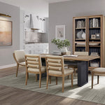 Modern dining room with wooden table and chairs, bookshelf, and kitchen in the background.