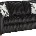 A black ribbed sofa with two black and white patterned accent pillows, shown against a plain white background.