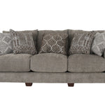 A three-seat upholstered sofa in a textured taupe-gray fabric, styled with five decorative throw pillows in gray and white geometric patterns, set against a plain white background.