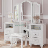 White vanity table set with a three-panel mirror, glass shelf, drawers, and a matching white stool in a softly styled bedroom interior.