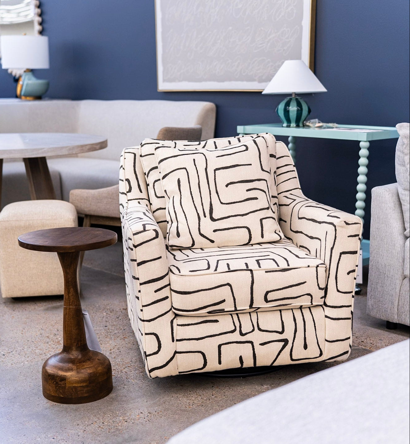 A modern accent chair upholstered in a cream fabric with a bold black geometric line pattern, styled in a contemporary living room setting.