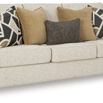 Beige sofa with patterned and solid color pillows on a white background. Alternative view.