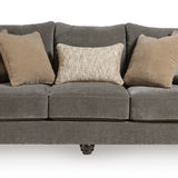 A three-seater upholstered sofa in dark gray fabric, styled with five throw pillows including two plaid and two solid beige/cream cushions, shown against a plain white background.