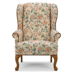 A classic wingback armchair upholstered in a beige fabric with a detailed floral vine pattern in orange and green, featuring dark brown wooden legs and trim.
