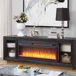 A modern dark gray electric fireplace TV stand console with a glowing orange and yellow flame effect, styled in a living room setting.