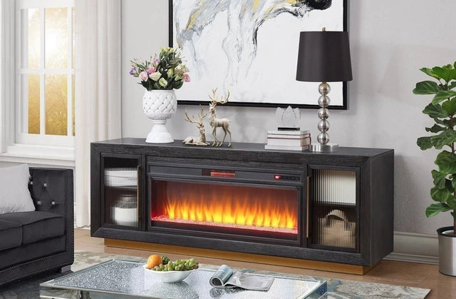 A modern dark gray electric fireplace TV stand console with a glowing orange and yellow flame effect, styled in a living room setting.