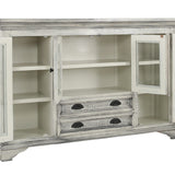 A distressed white wooden sideboard cabinet with glass doors, open to reveal shelves and two drawers with dark metal handles, shown on a plain white background.