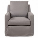 A modern slipcovered armchair in a light gray fabric, featuring a tall back cushion, square arms, and a skirted base, shown against a plain white background.
