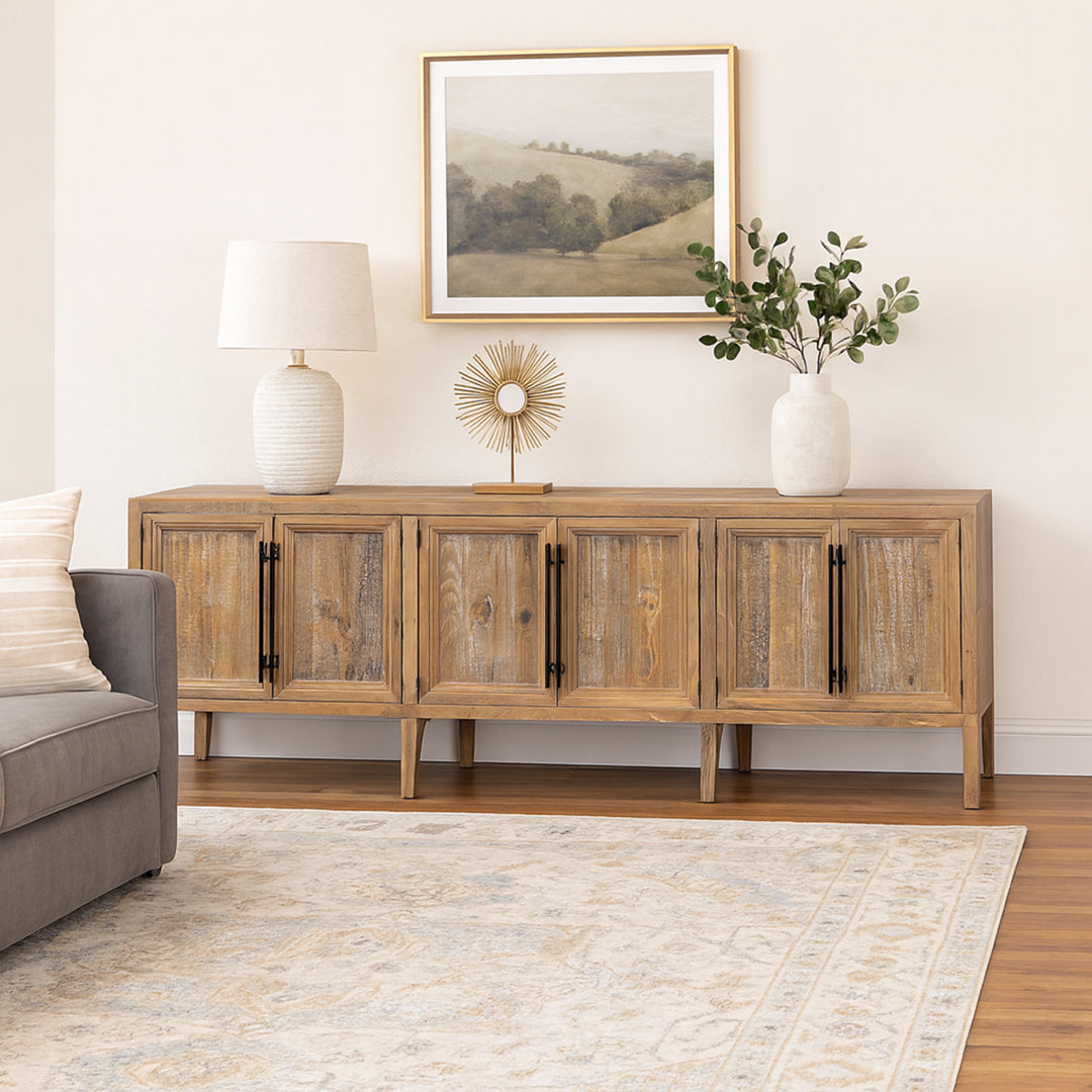 Wooden sideboard in a living room with decor items and a painting.