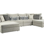 A light gray fabric sectional sofa with a chaise lounge on the left and a right-facing chaise, styled with multiple throw pillows including gray and patterned accent pillows, shown against a plain white background.