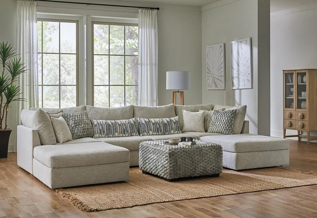 Modern living room with a beige sectional sofa, coffee table, and decorative pillows.