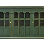 A green wooden cabinet with six glass-paneled doors arranged in three pairs of three arched windows each, featuring small brass knobs, shown against a plain white background.