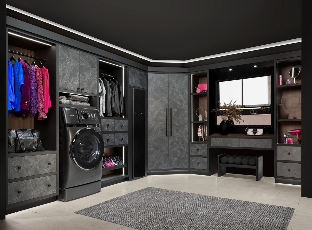 A luxury walk-in closet with dark gray and black custom cabinetry. Ft. GE Capacity Ultrafast Combo With Ventless Inverter Heat Pump Technology Washer/Dryer - Carbon Graphite