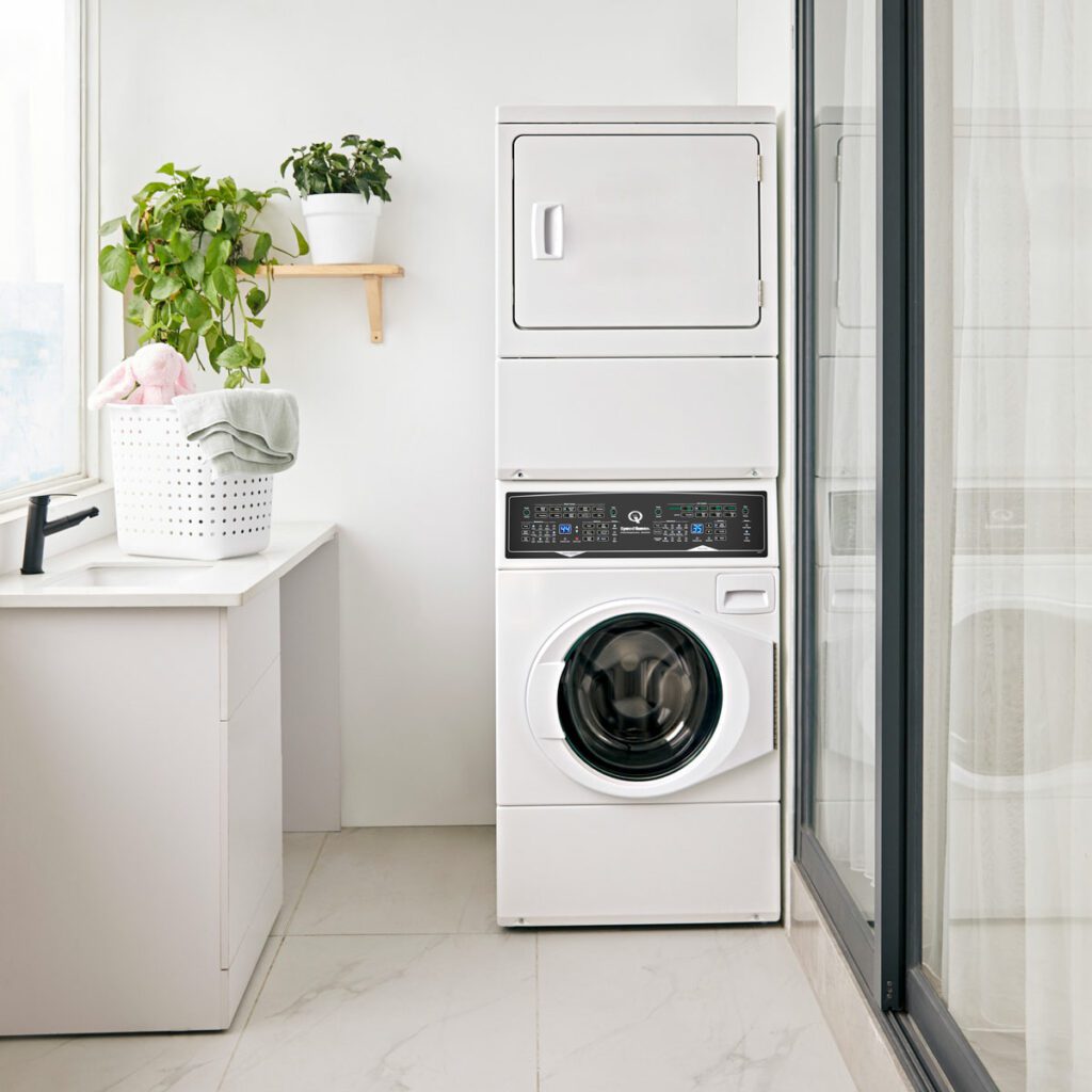 Modern laundry room with stacked washer and dryer, plant, and basket.